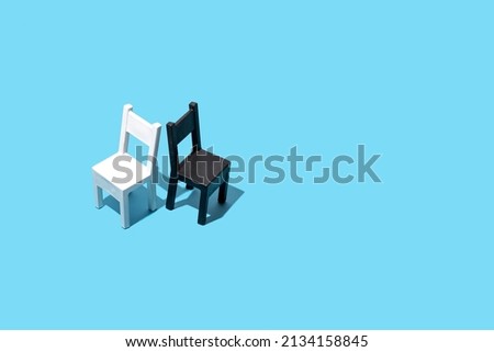 
Two chairs, black and white concept on a pastel blue background. Contrast, opposites, disagreement.  Royalty-Free Stock Photo #2134158845