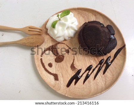 molten lava chocolate cake with whipping cream and penguin cartoon from coco powder as decoration on wooden dish