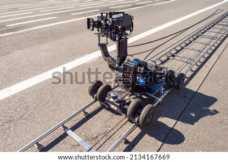 Trolley with professional video camera. Filmmaking equipment. Filming equipment on rails. Concept professional film shooting services. Video recording equipment. Rails with video camera on asphalt