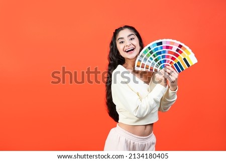 Cheerful woman with color palette fun on orange background with copy space.