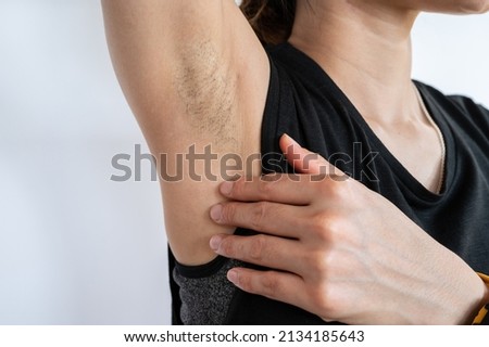 Close up of woman showing her unshaved armpit. Unshaven women often meet other criteria for traditional feminine beauty.