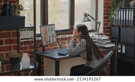 Frustrated employee working under pressure about deadline, using computer to plan business project. Overwhelmed woman feeling burnout at work in company startup office. Tired worker Royalty-Free Stock Photo #2134195267