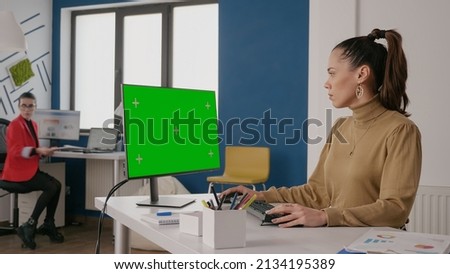 Business woman looking at green screen on computer, using isolated template and chroma key mock up template on monitor display. Employee working with blank copy space background.