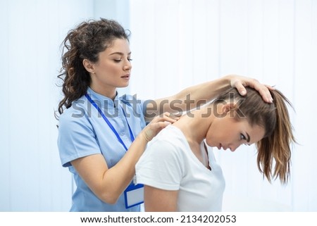 Licensed chiropractor or manual therapist doing neck stretch massage to relaxed female patient in clinic office. Young woman with whiplash or rheumatological problem getting professional doctor's help Royalty-Free Stock Photo #2134202053