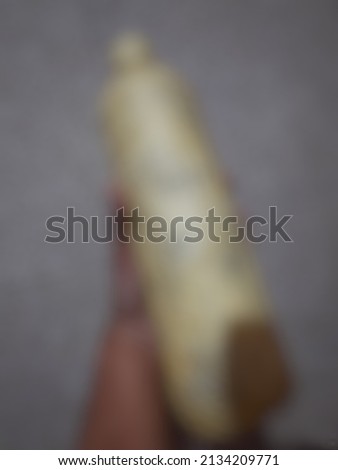 Defocused abstract background of a left hans holding a big plastic bottle that is used for saving money.