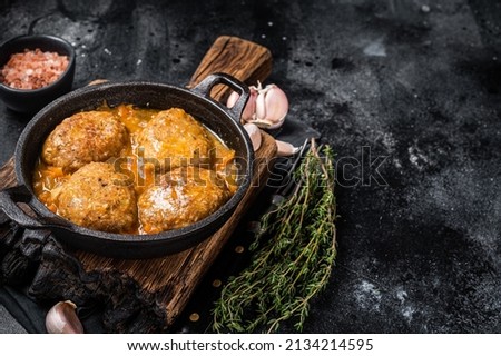 Fish balls with tuna in tomato sauce in a pan. Black background. Top view. Copy space