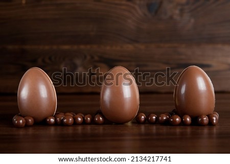 Happy Easter greeting card. composition with delicious sweets, chocolate eggs and blue bow on wooden background, space for text. Selective focus.