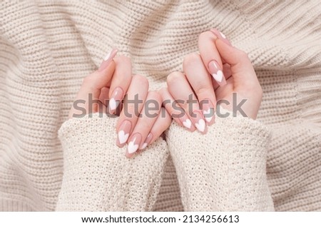female hands with beautiful long nails with  manicure with  heart pattern in winter clothes