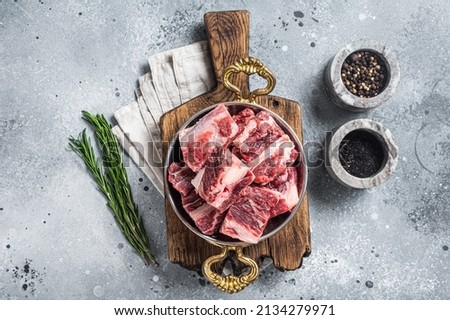 Fresh Raw diced beef marbled meat in steel skillet with herbs ready for cooking. Gray background. Top view