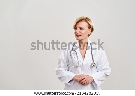 Partial image of focused female doctor looking away. Caucasian woman with stethoscope wearing white coat. Concept of medical and health care. Isolated on white background. Studio shoot. Copy space Royalty-Free Stock Photo #2134282019