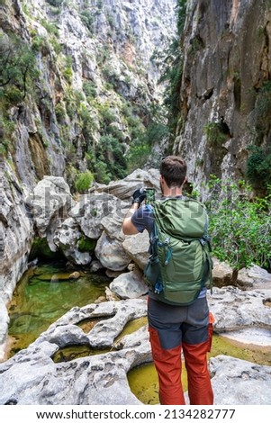 Active holiday on Mallorca: A photographing man Hikes through the exciting canyon, Torent de Parais gorge - exciting climbing