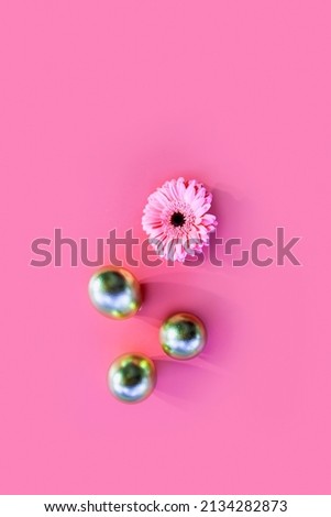 Golden colored Easter eggs and Gerbera daisy flower isolated on pink color background. Decorative Flat lay greeting advertising card spring Holiday concept. Copy space. Vertical image 
