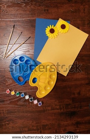 Top view picture of Ukrainian pictures with Ukrainian colours. Palettes in Ukrainians colours with paint and sunflower. High quality photo