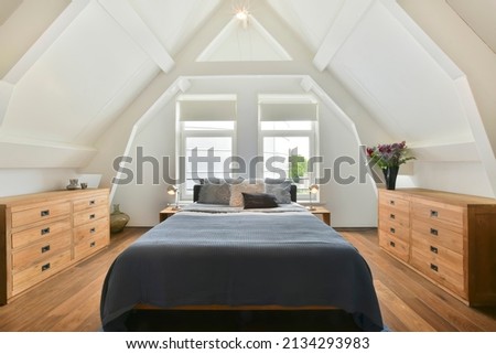 luxurious double bed with beautiful wooden furniture but located on the attic floor Royalty-Free Stock Photo #2134293983