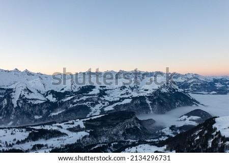 Amazing sunrise with red sky and a beautiful landscape in the wonderful region in Switzerland called Mythenregion. Beautiful mountain called Mythen and an epic sea of fog in the background.