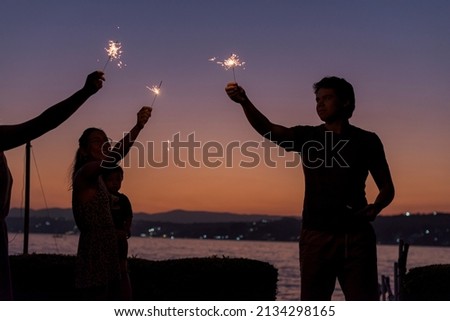 Silhouette of group of friends having playing with bengal lights Royalty-Free Stock Photo #2134298165