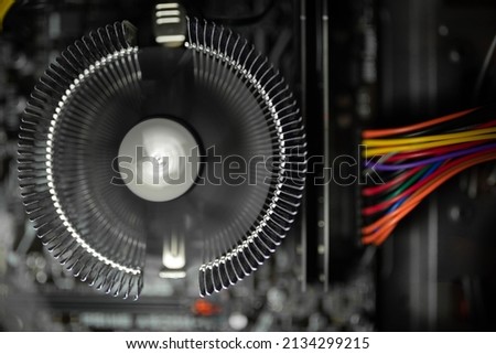 Computer fan spinning and cooling processor unit. Computer inside parts and wires closeup. 