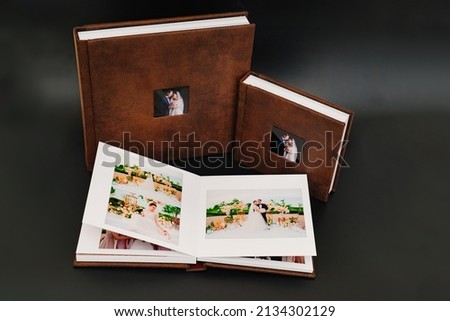 wedding photobooks in brown leather binding with photos on the cover. high-quality and expensive photo and printing products. services of a professional photographer and designer. on black background Royalty-Free Stock Photo #2134302129