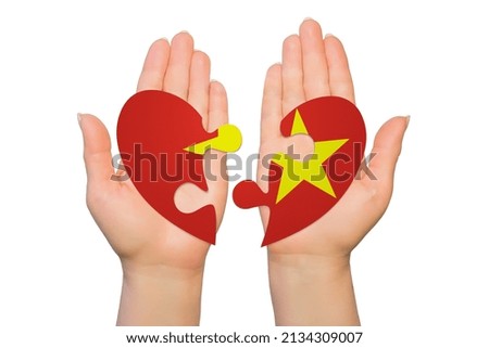Woman hands are holding two parts of puzzle heart. National concept on white background. Vietnam