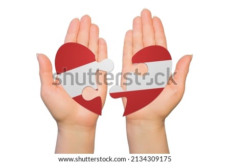 Woman hands are holding two parts of puzzle heart. National concept on white background. Austria