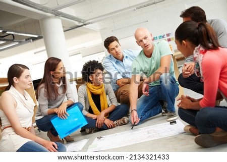 Dynamic designers. A group of multi-ethnic creatives huddled together and listening to the presentation of a plan. Royalty-Free Stock Photo #2134321433