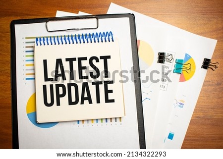 Notepad with text LATEST UPDATE with calculator and pen. White background. Business concept. High quality photo
