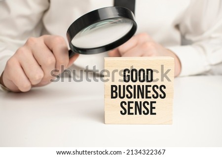 Magnifying glass with the word GOOD BUSINESS SENSE. Business concept. High quality photo