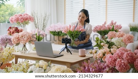 Asia girl vlogger influencer or SME owner people smile work on home video camera selfie shoot filming for live sell show happy talk on mobile VoIP app. Remote sale product at modern florist gift shop. Royalty-Free Stock Photo #2134329677
