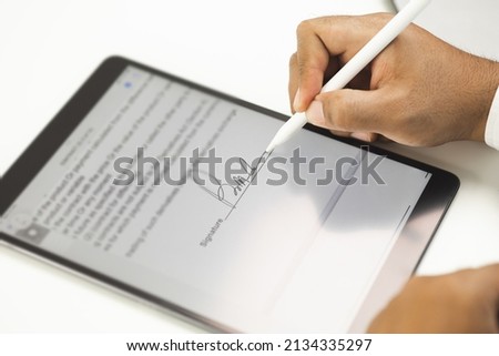 Close up businessman hand electronic Signature on Tablet by Stylus. Write business agreement of contract. Man signing contract on tablet. Business and technology concept.