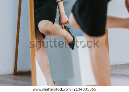 Asian woman putting on high heels to get ready for work