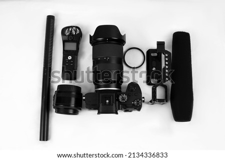 top view of photographer workspace with digital camera, microphone, grid, lens and recorder, on white table background
