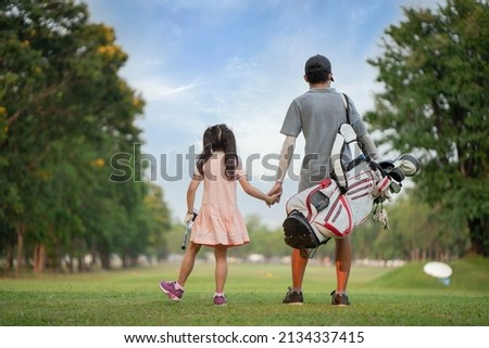 Brother takes his sister's hand to play golf.