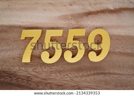 Wooden  numerals 7559 painted in gold on a dark brown and white patterned plank background.
