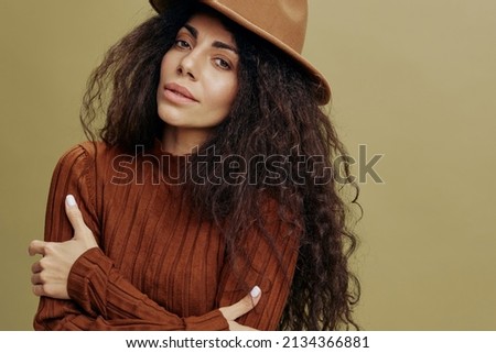 Modern style. Fashion Offer. Confident stylish curly Latin female in casual wear, smiling, look at the left, posing with folded arm, isolated green background. Mock up copy space free place ad. 