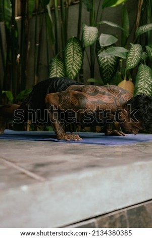 Young latin american tattooed man practice yoga outdoors during retreat vacation in Bali, stretching, meditation, wellness