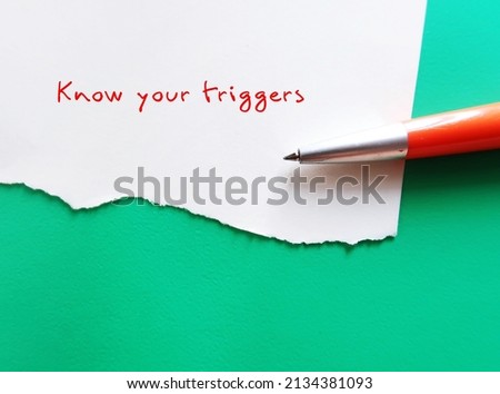 On green copy space background, pen writing on torn paper KNOW YOUR TRIGGERS, learning to know experience of having emotional reaction to a disturbing topic in media or social setting and cope with it Royalty-Free Stock Photo #2134381093