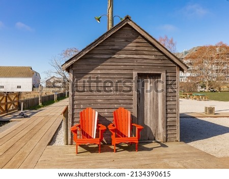Two Adirondack chairs on a wooden dock by the small wooden cabin. Travel photo, nobody, selective focus