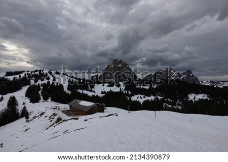 Great long exposure that stretches the clouds and a mighty mountain in the picture called Grosser Mythen in the canton of Schwyz in Switzerland with a small log cabin in the foreground.