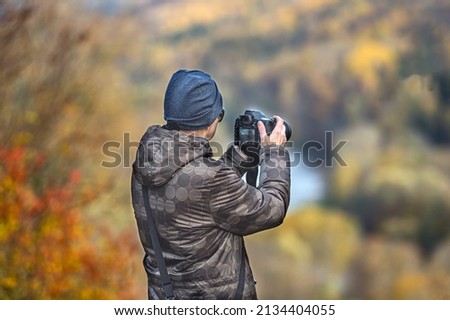 back view of Young photographer takes pictures of autumn landscape, closeup