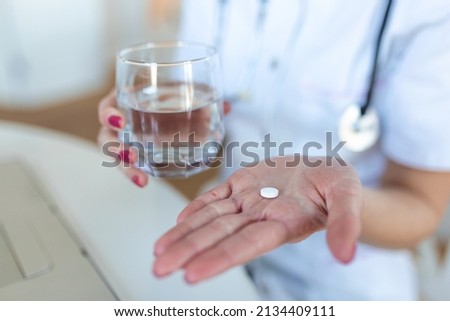 Female doctor having online therapy with her patient's, giving them advice while holding a pill and glass of water in her hands
