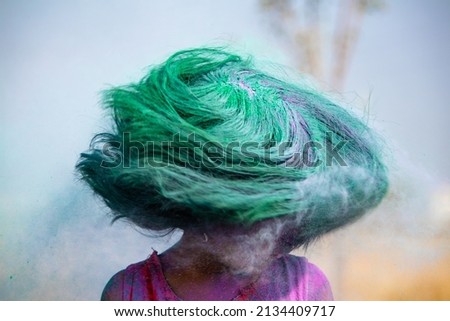 slow shutter speed shot of gil kid shaking head with holy colors during festival - concept of Indian culture, entertainment and festival celebration
