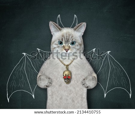 An ashen cat with a skull medallion is standing near a blackboard on which are painted the wings of a bat and horns.