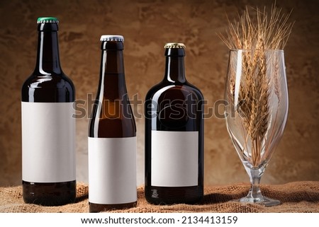 Beer bottle and beer glass against gray background, front view