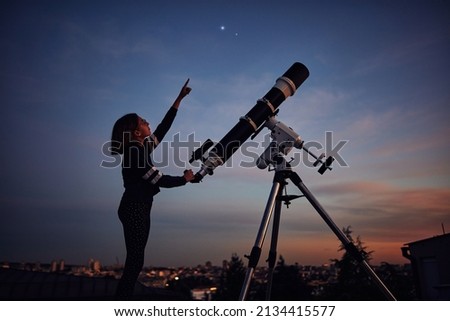 Girl with astronomical telescope stargazing under twilight sky. Royalty-Free Stock Photo #2134415577