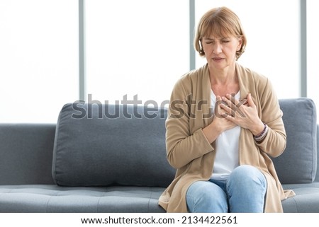 senior woman pain suffering from heart disease on sofa Royalty-Free Stock Photo #2134422561