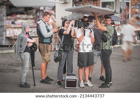 Behind the scenes. Film crew team shooting movie scene on outdoor location. Group filmmaking set production Royalty-Free Stock Photo #2134443737