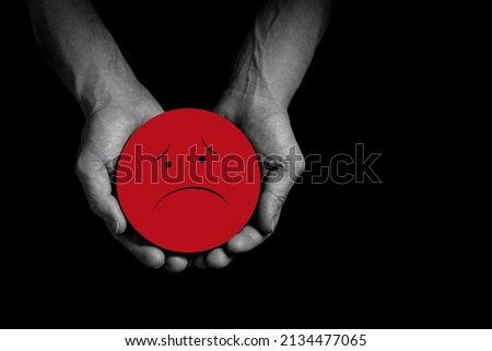 Hands holding sad smile, bad feedback rating, negative customer review, bad experience, unsatisfied survey, mental health assessment, child wellness concept, Red face on black background copy space. Royalty-Free Stock Photo #2134477065