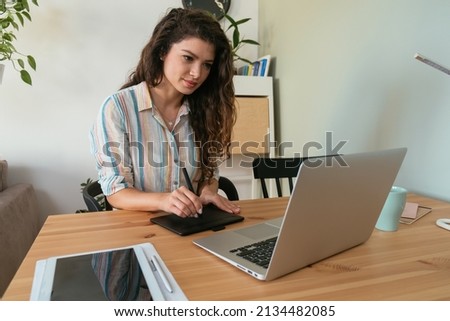 Happy Business Woman Working at Home on her Laptop Computer and Retouching Pad