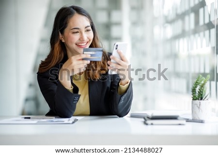 Young Asian woman orders goods online using a laptop and a credit card. Online shopping, delivery and payment systems concept.