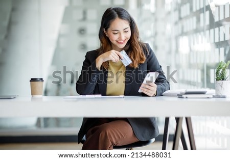 Young Asian woman orders goods online using a laptop and a credit card. Online shopping, delivery and payment systems concept.